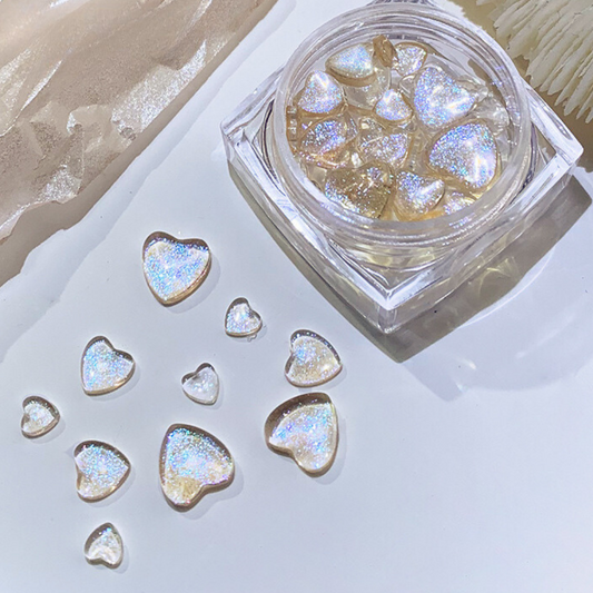 Close-up view of a jar filled with aurora-colored heart glitter gems, displaying a sparkling iridescent finish ideal for captivating nail designs.