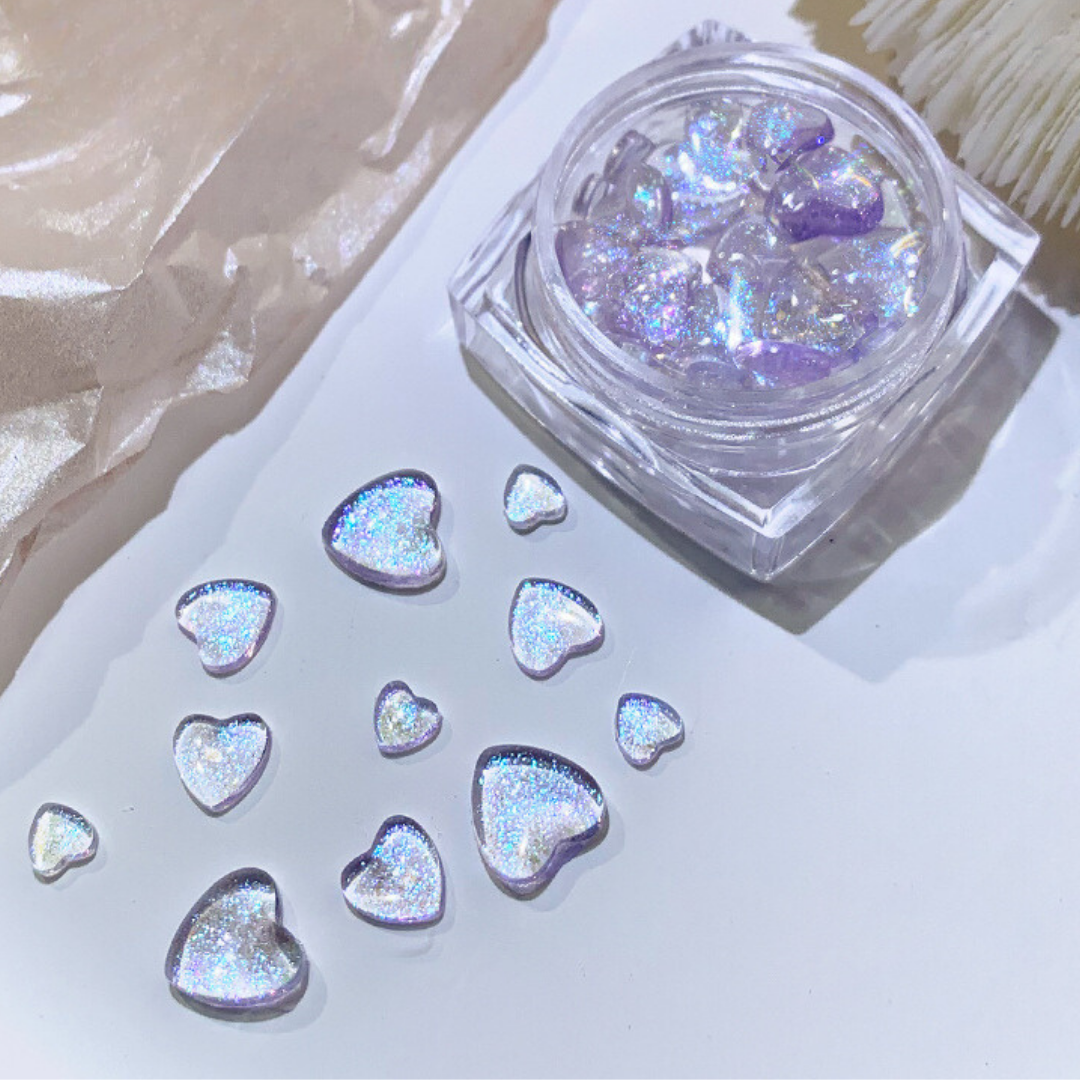 Purple heart glitter gems in varying sizes, stored in a clear jar, showcasing a cool-toned sparkle for trendy and stylish nail art.