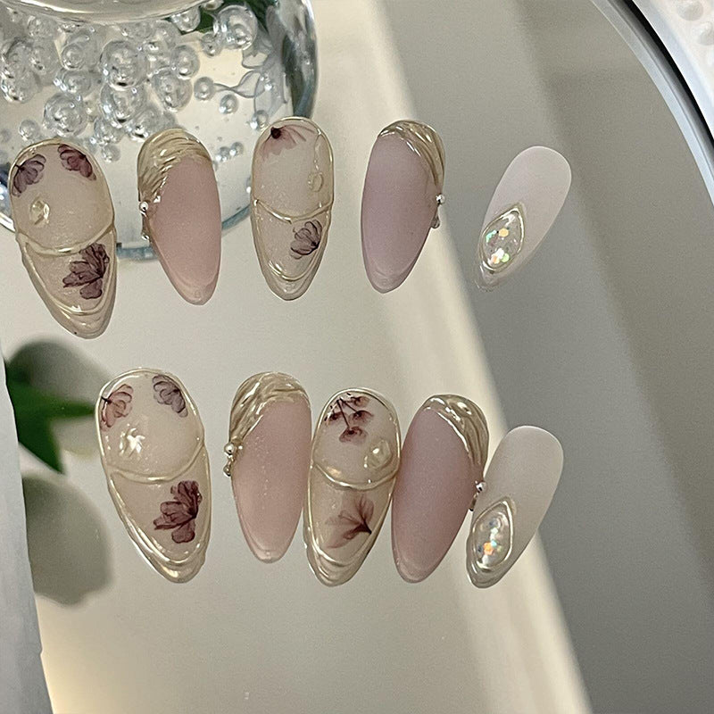 Set of 'Floria' press-on nails featuring a blend of transparent and matte pink shades with embedded floral designs, perfect for a soft, natural look.