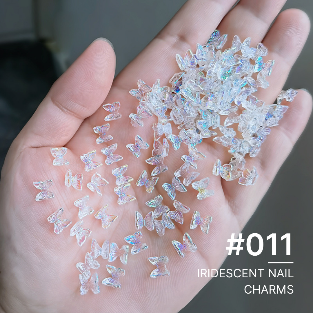 Handful of various iridescent nail charms including stars, flowers, and butterflies, ideal for diverse and dynamic nail art creations.