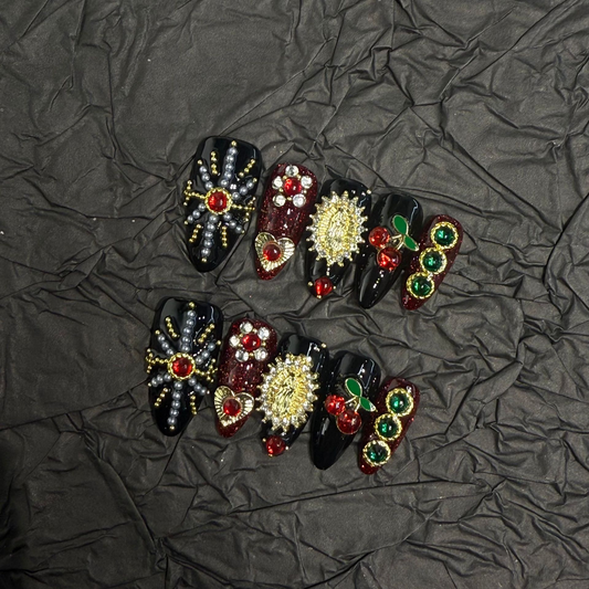 Angled view of black burgundy glitter almond nails with cherries and gold-tone details