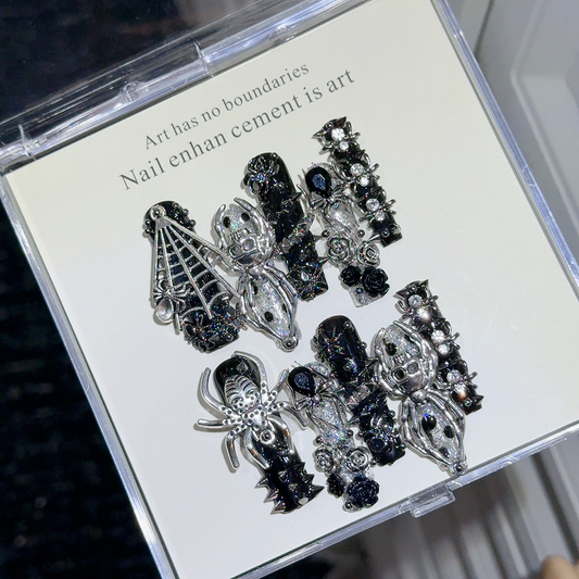 Angled view of black glitter gothic press-on nails with silver-tone spiders and roses