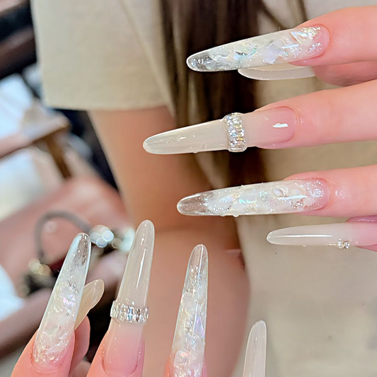 Close-up of glossy shell accent press-on nails with silver crystal-look details