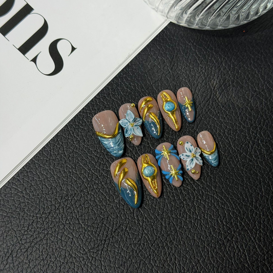Blue and gold almond press-on nail set with raised flowers and starburst details