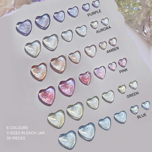 Array of heart-shaped glitter gems in six colors including purple, aurora, amber, pink, green, and blue, showcased on a white background for nail art enhancements.