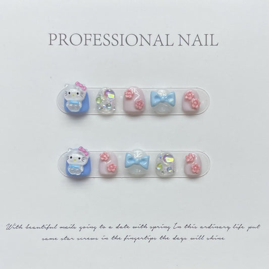 Hello Kitty - Blue press-on nails displayed on a professional card, featuring light blue and clear nails with cute Hello Kitty figures, pink flowers, and blue bow accents.