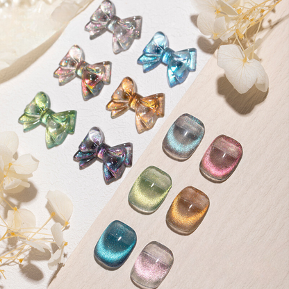 An assortment of cat-eye gel polishes in various iridescent colors, arranged alongside matching decorative bows. The polishes display a shimmering, multi-dimensional effect, capturing light to create a cat-eye appearance on the nails.