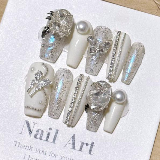 Press-on nails from the 'Diamonds and Pearls' collection displayed on a card, featuring intricate designs with glitter, rhinestones, and pearl embellishments, suitable for elegant nail art enthusiasts.