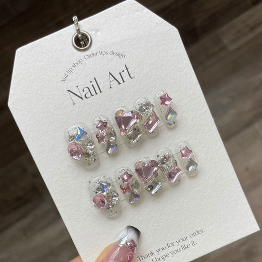 Set of 'LOVE SPELL' press-on nails featuring a romantic design with deep red hues and sparkling accents, ideal for elegant and glamorous nail looks.