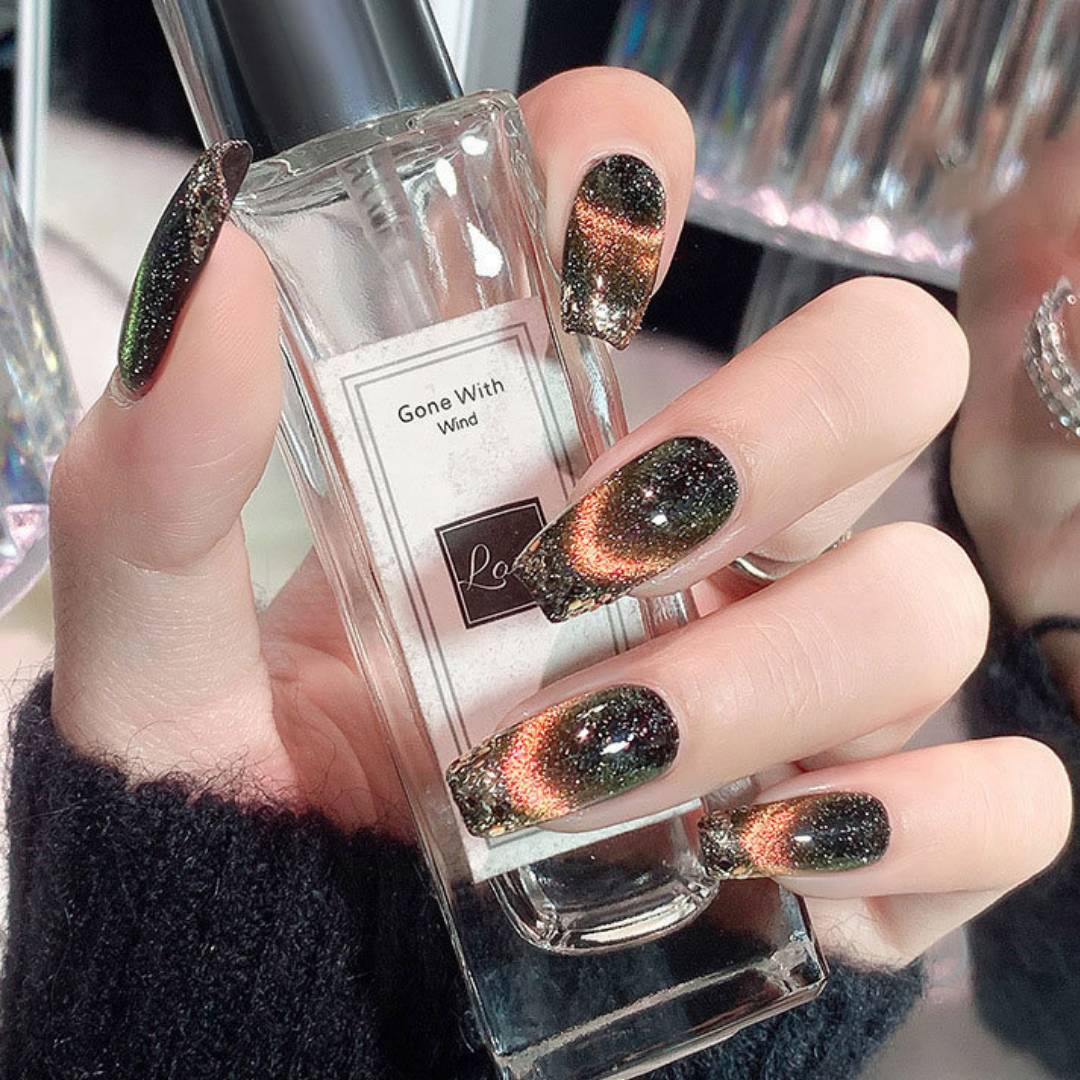 Close-up of nails with a cat eye effect: "Close-up view of fingernails painted with BOMD cat eye gel polish, featuring a mesmerizing magnetic shimmer effect in a black and orange shade."