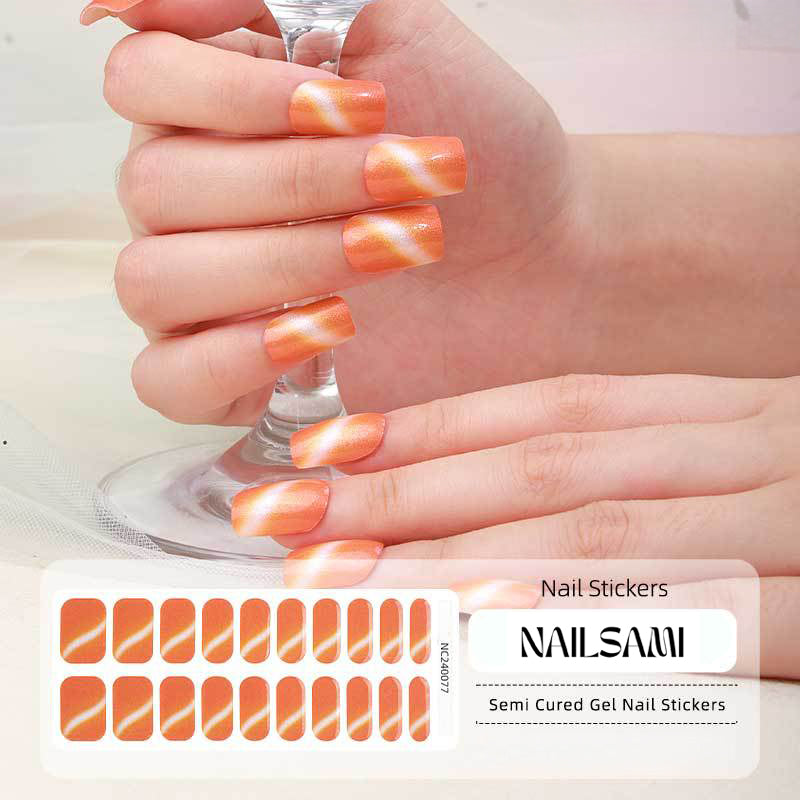 Hand with nails in a warm amber gradient gel nail sticker design, with a NAILSAMI gel nail sticker sheet displayed below featuring the same amber and golden design.