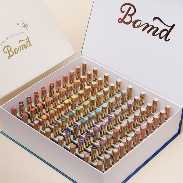 A beautifully presented box set of BOMD gel polish, showcasing an extensive array of colors neatly arranged in rows. Each bottle is topped with a shiny, gold cap, and the collection is elegantly displayed inside a branded BOMD box, highlighting the premium and organized nature of the product offering.