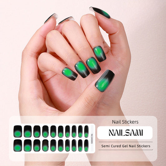 Hand with nails in a deep green to black gradient gel nail sticker design, with a NAILSAMI gel nail sticker sheet displayed below showcasing the same green and black design.