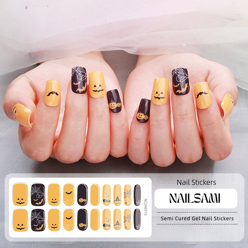 Hand with nails featuring a Halloween-themed yellow and black gel nail sticker design with spooky smiley faces, with a NAILSAMI gel nail sticker sheet displayed below showcasing the same festive design.