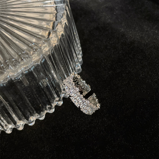 Silver-tone zircon-set adjustable ring beside a glass jewellery box