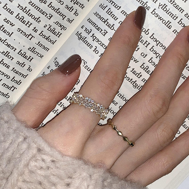 Gold-tone zircon-set and wavy metal rings worn together
