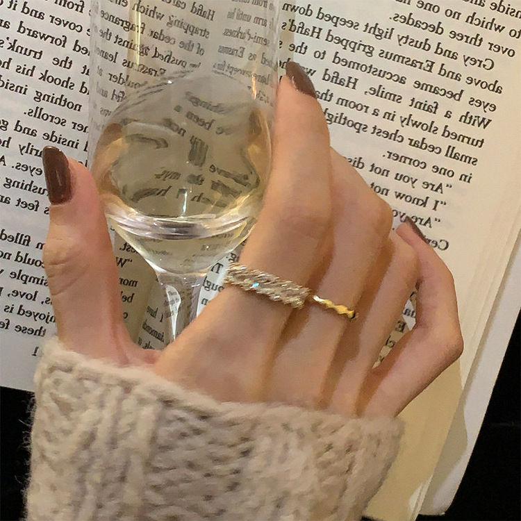 Gold-tone zircon-set and wavy metal adjustable rings styled on a hand