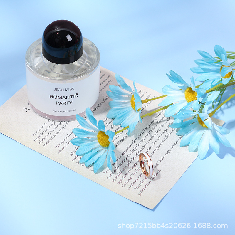 Blue artificial daisy flower spray styled with a perfume bottle and ring