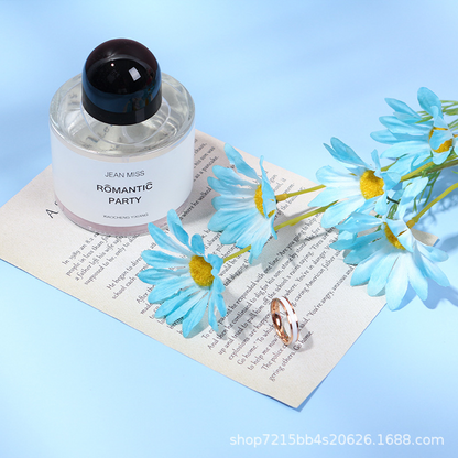 Blue artificial daisy flower spray styled with a perfume bottle and ring