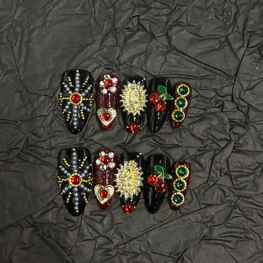 Black and burgundy almond press-on nails with a beaded cross and colourful raised accents