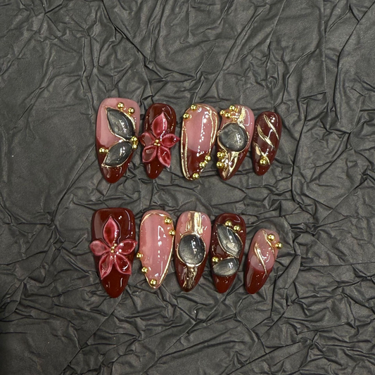 Burgundy floral cat-eye almond press-on nails with nude pink and gold-tone accents