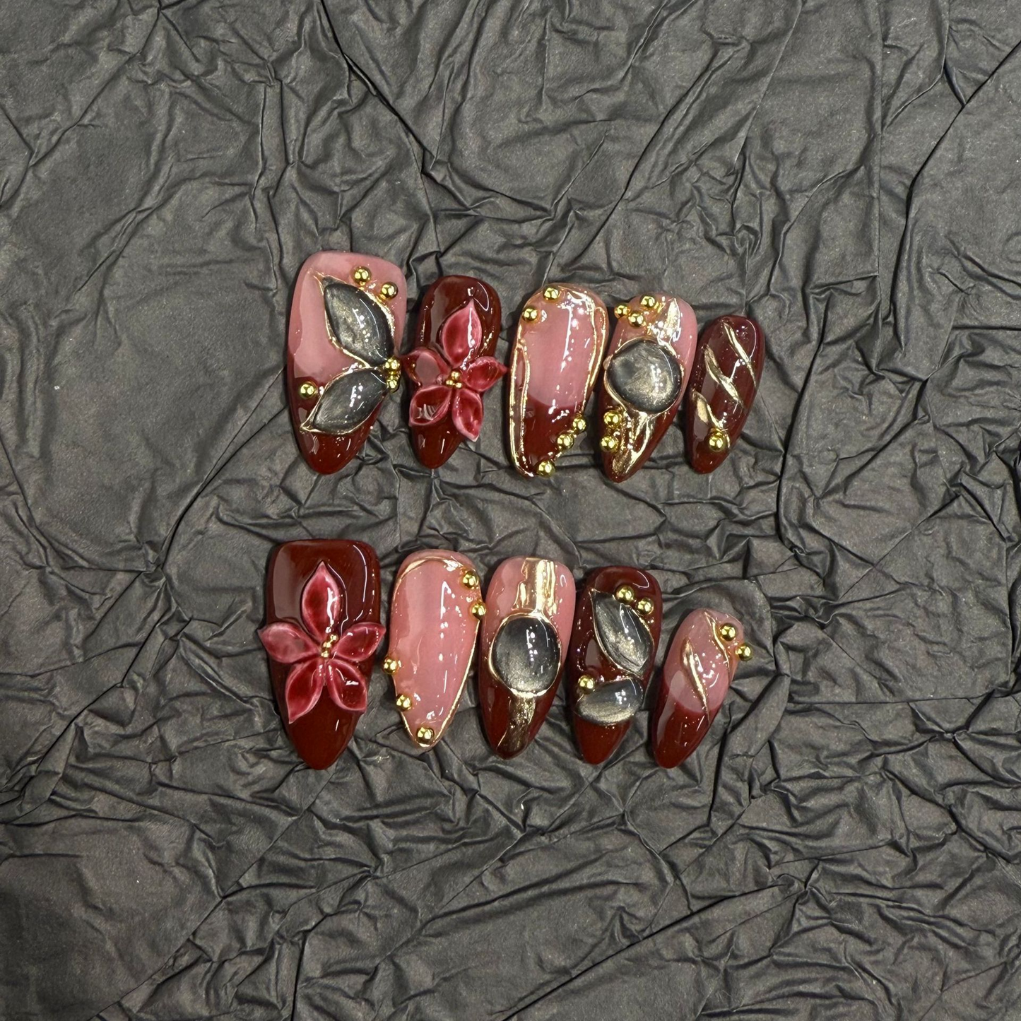 Almond press-on nail set with burgundy panels, raised flowers and smoky cat-eye details