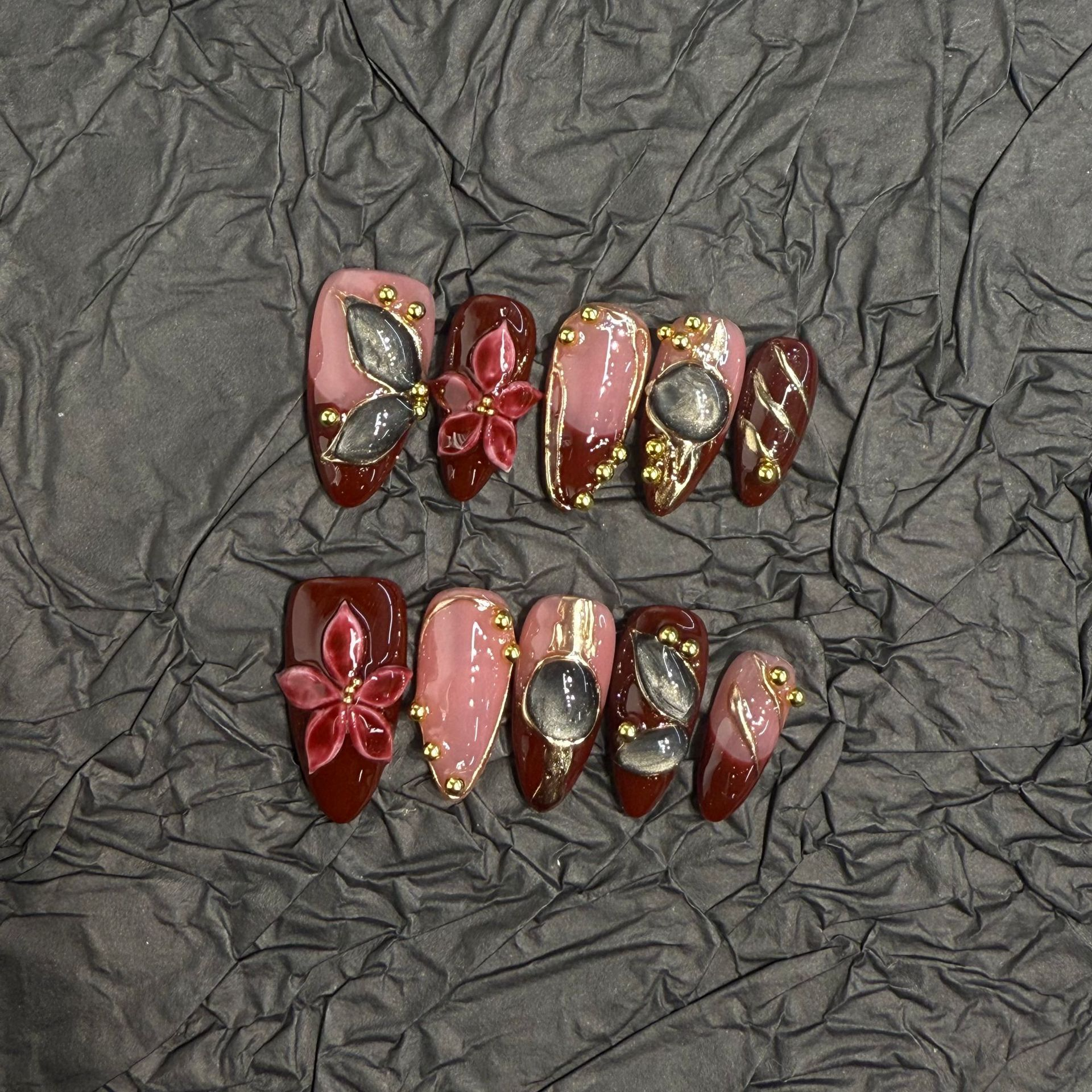 Almond press-on nail set with burgundy panels, raised flowers and smoky cat-eye details