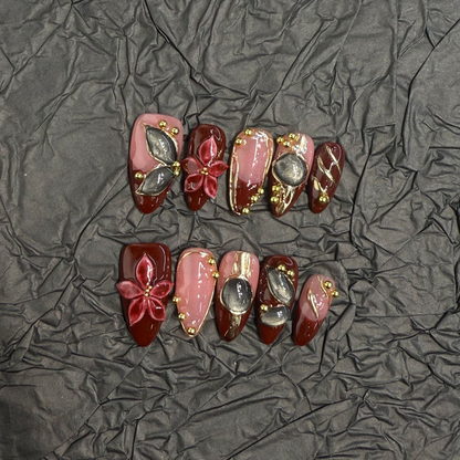 Almond press-on nail set with burgundy panels, raised flowers and smoky cat-eye details