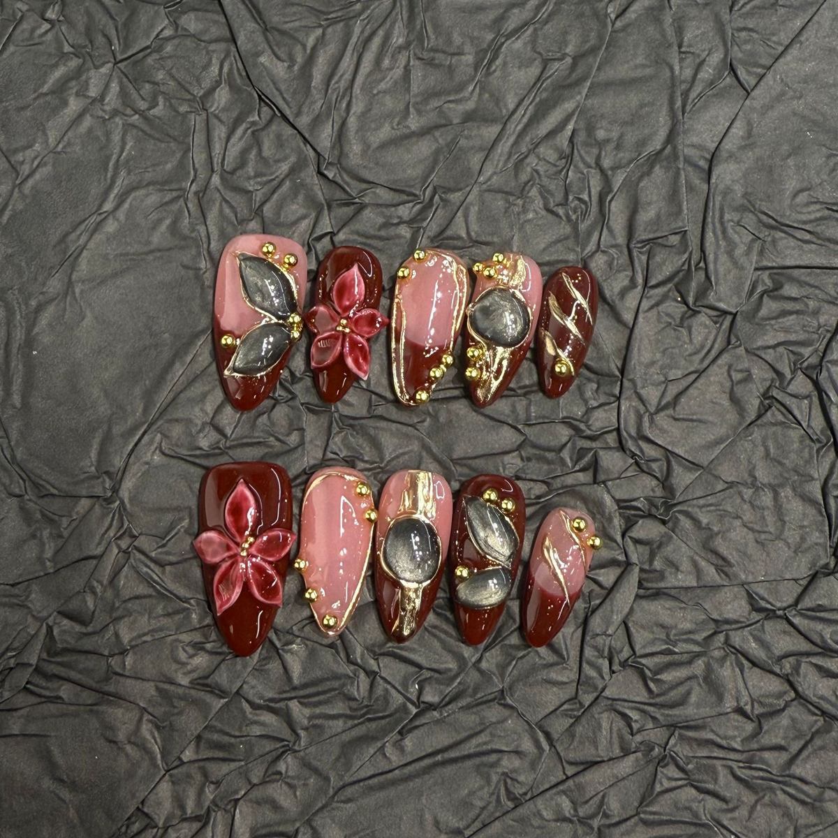 Vintage-inspired burgundy and nude almond press-on nails with gold-tone linework