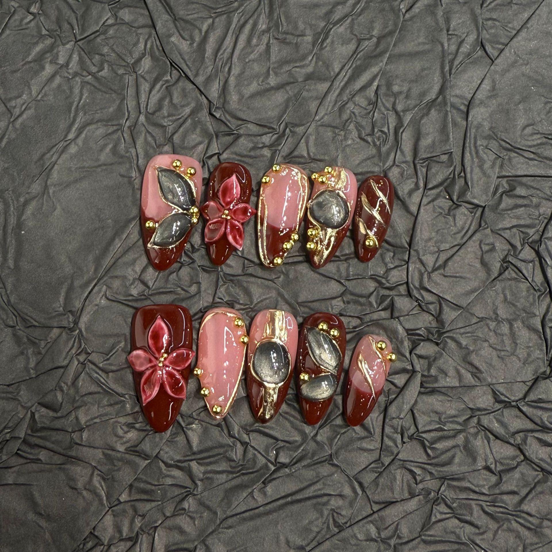 Vintage-inspired burgundy and nude almond press-on nails with gold-tone linework