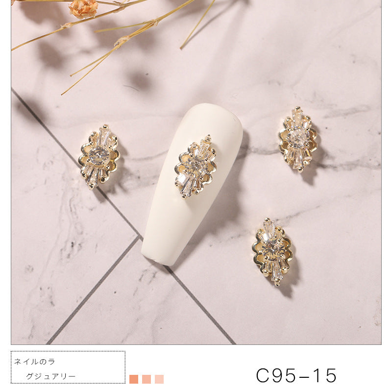 A luxurious nail charm featuring a central round crystal surrounded by an elegant arrangement of smaller baguette-cut crystals. The design is set in a gold-toned metal, giving it a sophisticated and dazzling appearance. The charm is suitable for enhancing nail art with a touch of glamour and elegance.