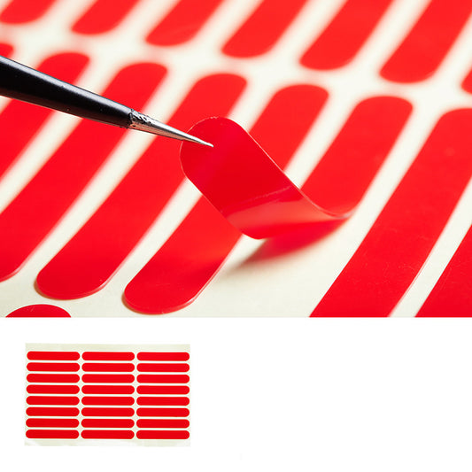 A sheet of vibrant red nail decals, featuring elongated, rounded strips designed for easy application. A precision tool is shown lifting one of the decals, demonstrating their flexibility and ease of use. These nail decals are perfect for creating bold and striking nail designs, offering a quick and convenient way to add color and style to any manicure.