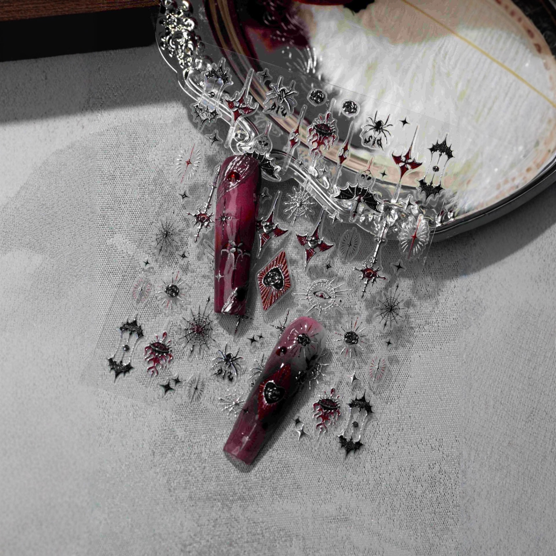 Close view of red black and silver gothic Halloween nail stickers with finished nail examples