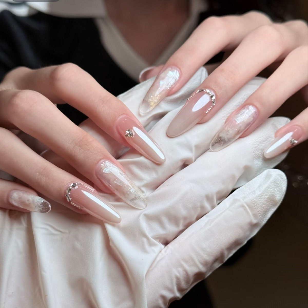 Sheer nude and white almond press-on nails with silver flake and crystal-look embellishments