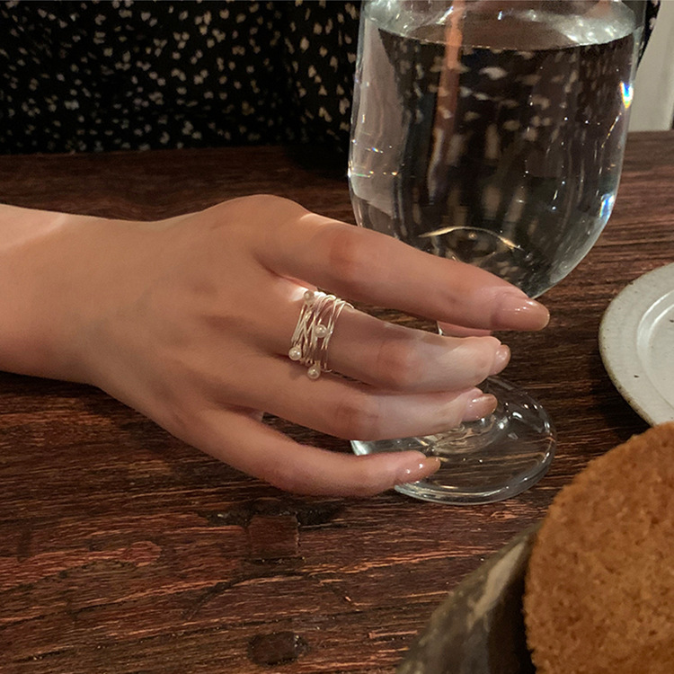 Close view of an irregular multi-layer pearl open ring worn on a hand