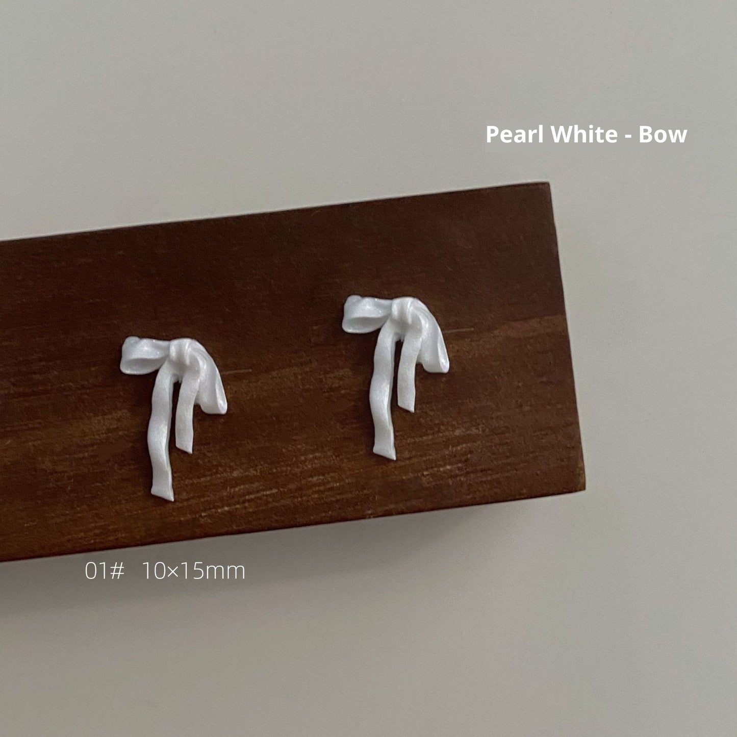Pearl white resin bow style 1 measuring approximately 10 by 15 millimetres