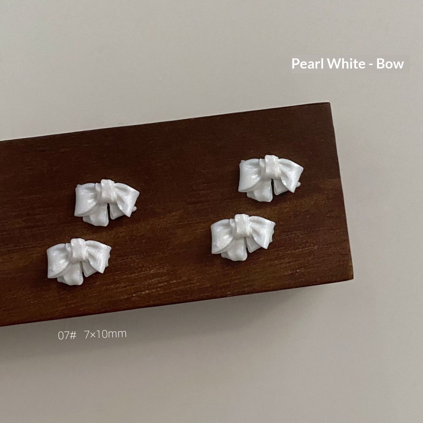Pearl white resin bow style 7 measuring approximately 7 by 10 millimetres