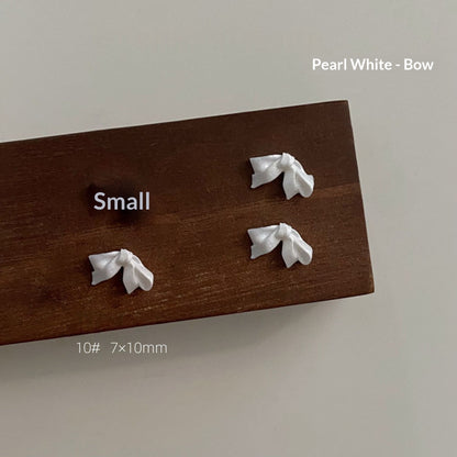Small pearl white resin bow style 10 measuring approximately 7 by 10 millimetres