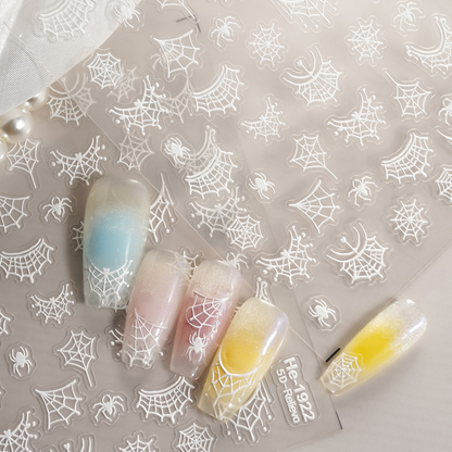 White embossed spider and spider web nail sticker sheet with pastel nail examples
