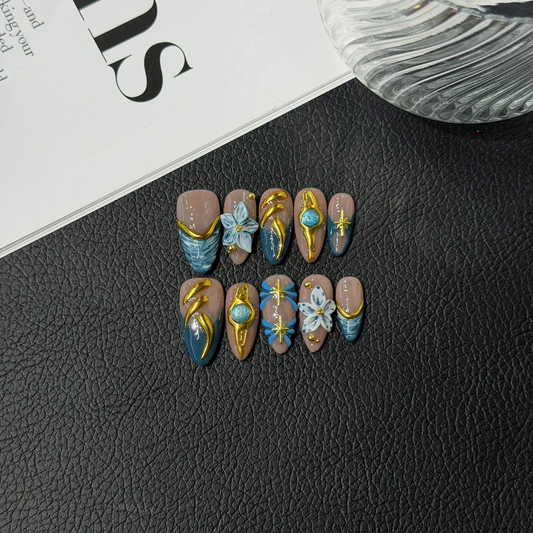 Teal floral almond press-on nails with translucent nude and sculptural gold-tone accents