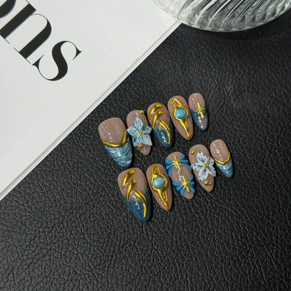 Blue and gold almond press-on nail set with raised flowers and starburst details