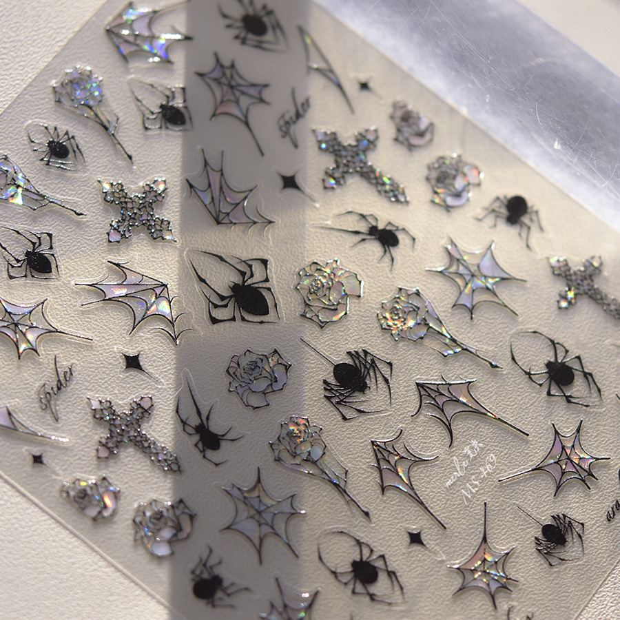 Close-up of TOMONI MS469 dark crosses black spiders and iridescent web nail stickers