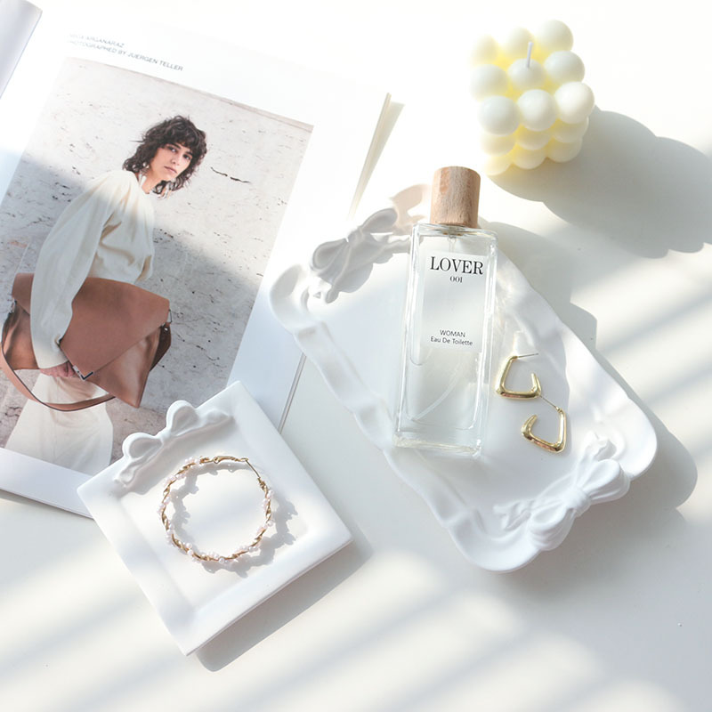 White bow plaster trays styled with perfume, earrings and a bracelet